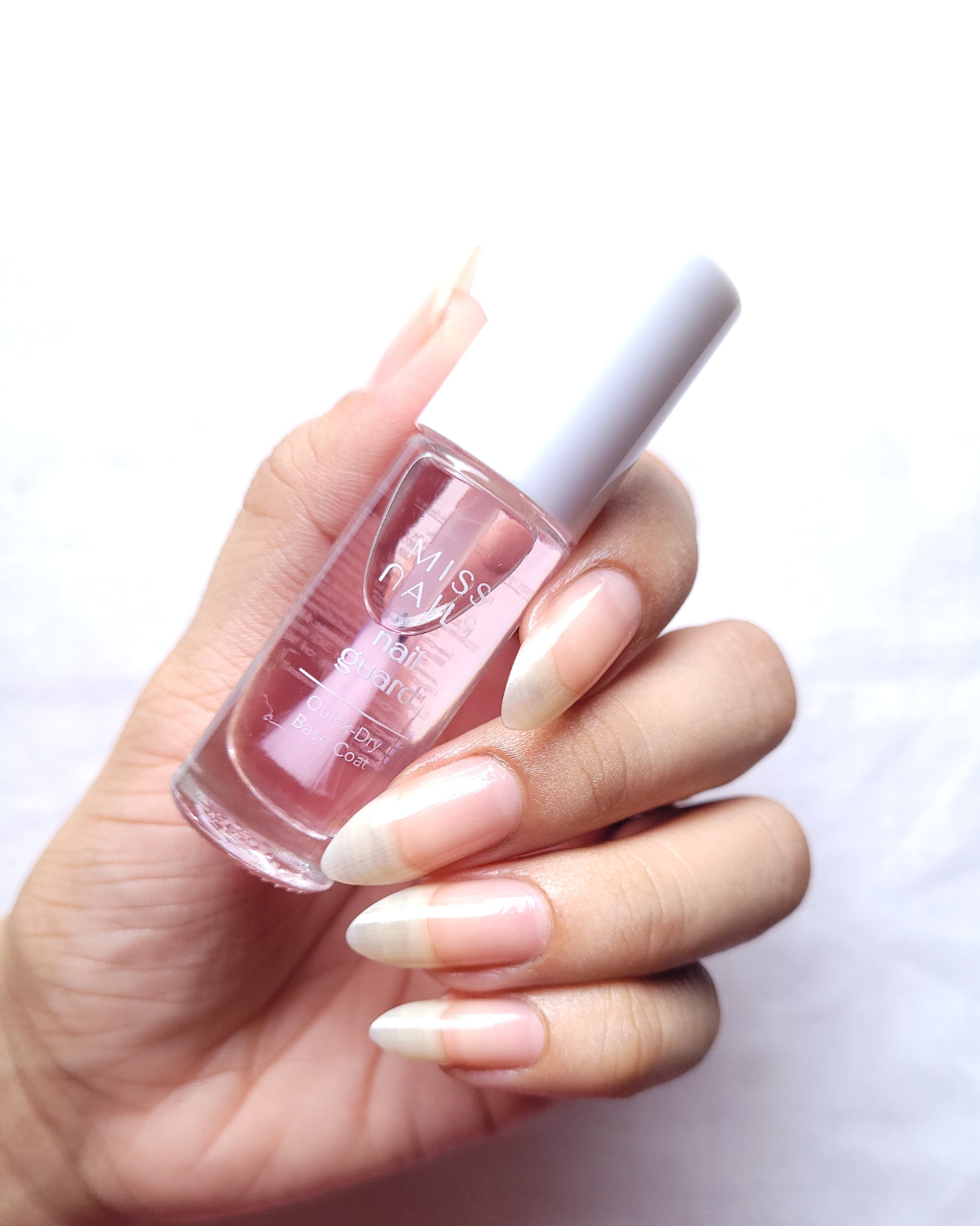 Hand holding a bottle of base coat
with a white background