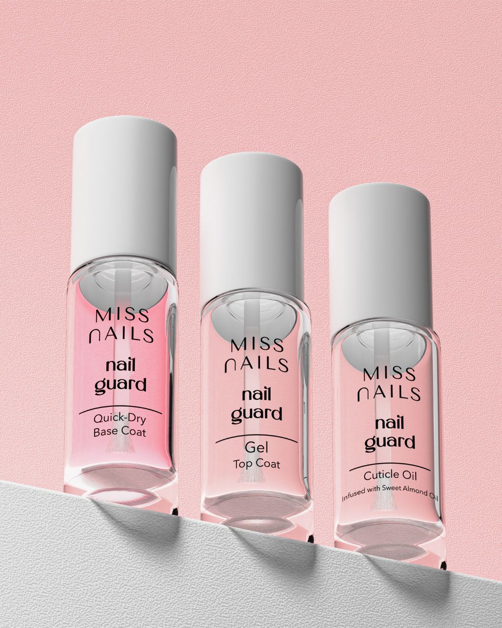 Three bottles of 'MISS NAILS' nail care products, top on a pink backgroundcoat, base coat, and cuticle oil,