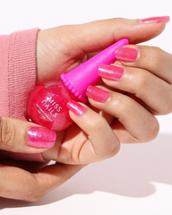 Hand holding a pink nail polish bottle with a matching pink brush applicator against a white background